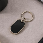 Oval metal keychain with glossy black center and polished silver frame