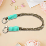A phone with a vibrant multi-colored phone wrist strap attached, held securely.