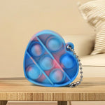 Several mini fidget keychains in various shapes and colors, demonstrating their compact size and portability.