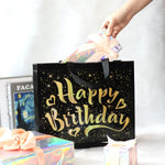 Close-up of golden star design on black reusable birthday gift bag