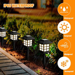 Two solar pathway lights installed along a garden path, casting warm light.