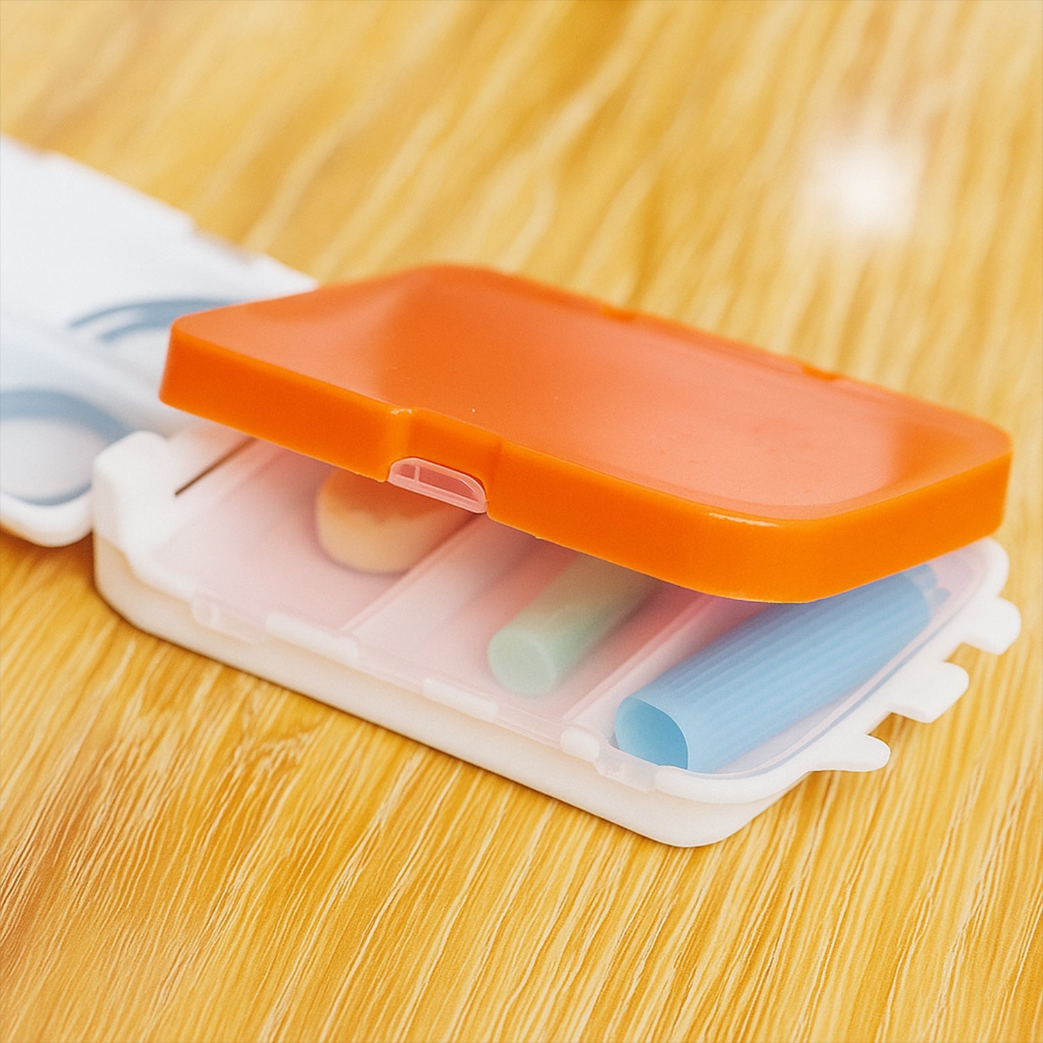 Side angle view of portable orange pill organizer for daily meds