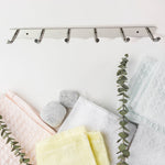 Modern home setting featuring wall mounted stainless steel coat rack with 6 hooks
