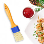A red cooking brush evenly basting meat on a grill.