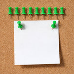 Green push pin fixing paper on a cork notice board