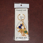 Golden Krishna Peacock keychain packaged in a Peepal Leaf blister pack