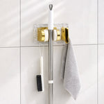 Space saving broom and mop hanger wall mounted with self adhesive base