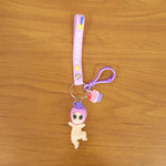 Detailed close-up of doll and cupcake charms on colorful rainbow strap keychain