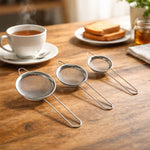 Multiple tea strainers lined up on table