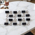 Pile of black metal binder clips 19mm size together