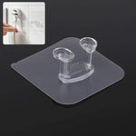 Transparent self-adhesive wall hook mounted on a clean, smooth wall.