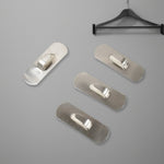 Two stainless steel self-adhesive hooks neatly holding towels in a modern bathroom.