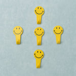 A set of five white self adhesive hooks displayed on a clean surface.