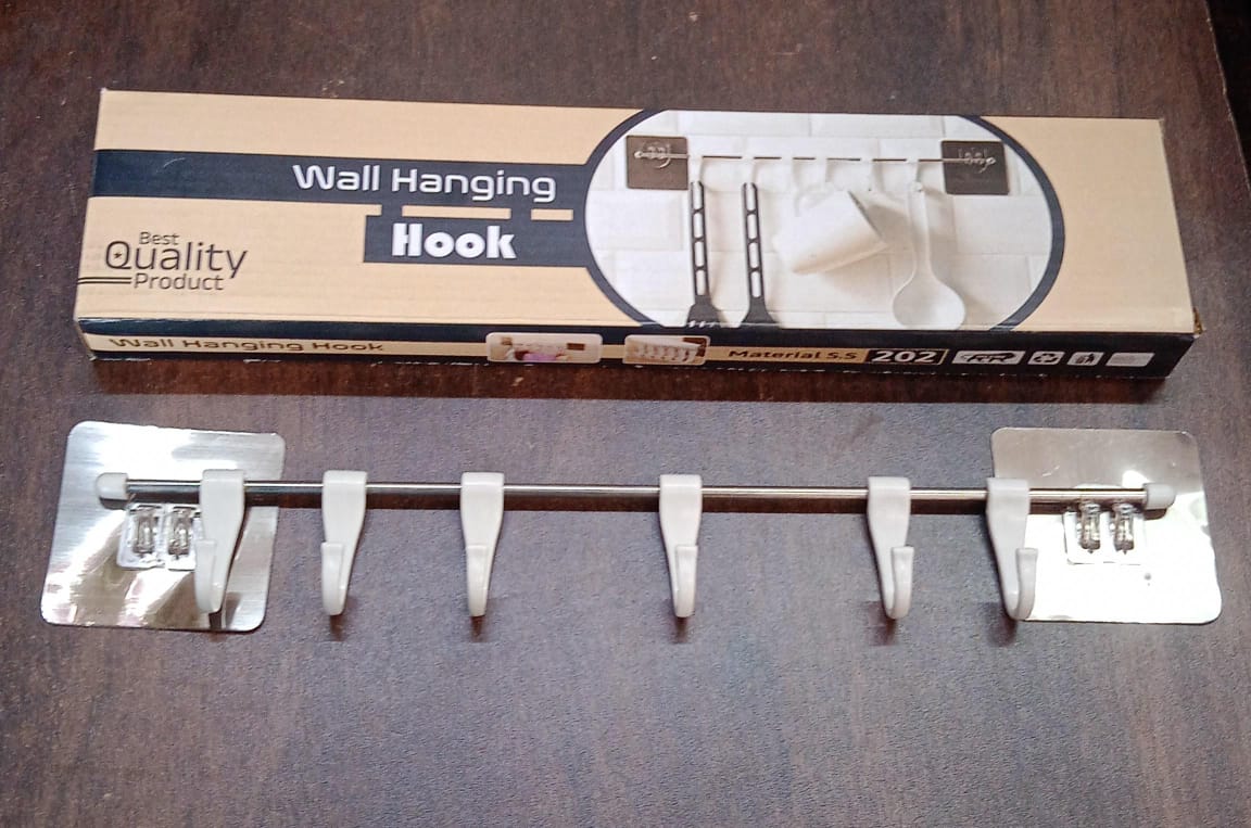 A functional stainless steel utensil hanger rail installed in a modern kitchen, with cooking utensils hanging.