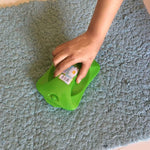 Handheld carpet roller brush efficiently cleaning dust and crumbs from a patterned rug.