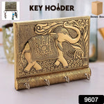 Close-up of the polished gold elephant head and hooks on the wooden key holder.