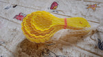 A perfectly shaped ladoo sits next to the plastic mould spoon used to create it.