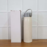 Lifestyle shot featuring the glass water bottle with phone holder in a natural setting.