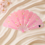 Foldable floral hand fan resting elegantly on table