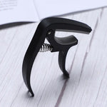 Guitar capo and pick holder positioned on a guitar neck, ready for playing.