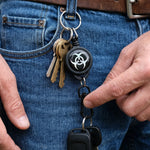 Hand holding a compact retractable keychain with sturdy clip.