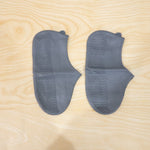 Waterproof silicone shoe covers being worn by a person walking through a muddy park.