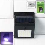 Solar powered LED wall light with motion sensor illuminating garden pathway