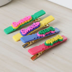 Sweet Text hair clips shown on a neutral background