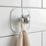 Close-up of clear plastic adhesive wall hook holding a kitchen towel securely.