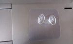Minimalist transparent self-adhesive wall hook installed on a white wall.