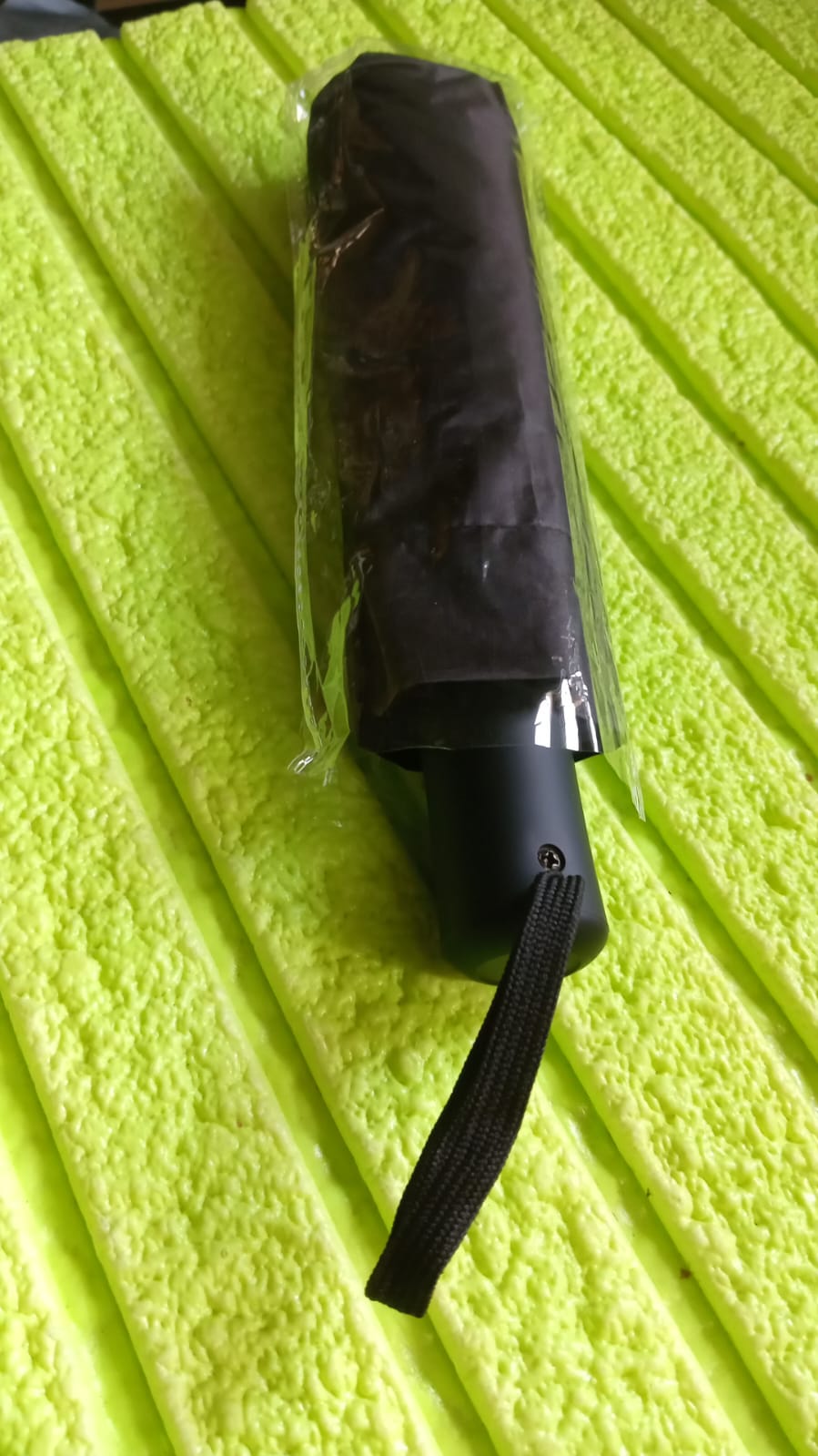 Folded black manual umbrella with a practical wrist strap shown on a clean white background.