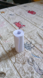 An overhead view of the thermal printer paper roll and a mini printer on a workspace.